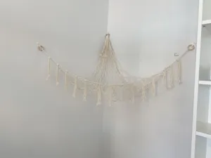 Handmade macrame toy hammock for corner, beige cotton rope storage net with tassels.