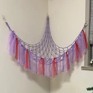 Handcrafted macrame toy hammock with colorful ribbons for kids room corner toy storage net.