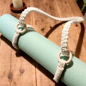 Cinghia per tappetino yoga in macramè fatto a mano con anelli di legno sul tavolo