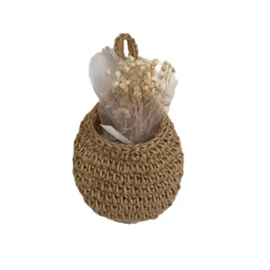Handmade woven jute hanging basket with dried flowers, wall-mounted rustic kitchen storage.