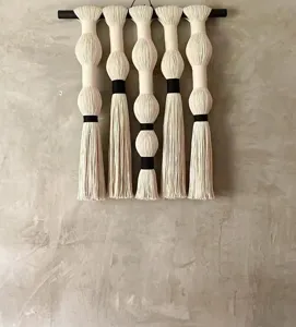 Handgemaakte katoenen macrame wandhanger met bolvormige kwastjes, boho interieur slaapkamer.