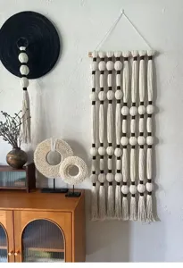 Detail van handgemaakte macrame wandhanger met katoenen kwastjes en houten kralen voor thuis