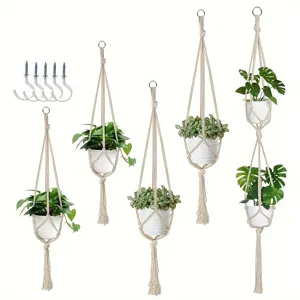 Colgador de plantas en macramé hecho a mano con macetas blancas y ganchos de pared.