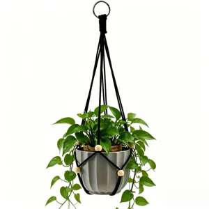 Colgador de plantas de macramé negro hecho a mano con maceta gris y planta colgante.
