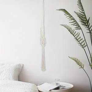 Gedetailleerd overzicht van handgeweven plantenhanger in minimalistisch wit interieur.