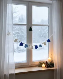 Primo piano della ghirlanda lavorata a mano con cappelli e guanti su una finestra innevata.