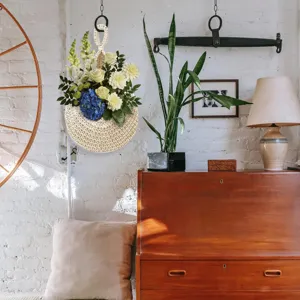Handgemachter gewebter Hängekorb mit künstlichem Blumenstrauß für schöne Wanddekoration.