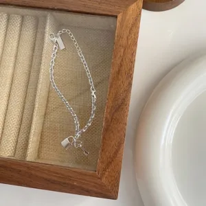 Zilverkleurige armband met fijn slot en sleutelhanger, elegant accessoire voor dames en meisjes.