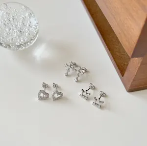 Detailaufnahme von Ohrsteckern aus Sterlingsilber mit Herzen, Kreuzen und Kronen.