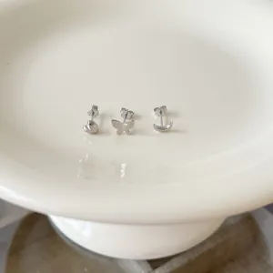 Close-up detail view of cute sterling silver stud earrings featuring heart, butterfly and moon.