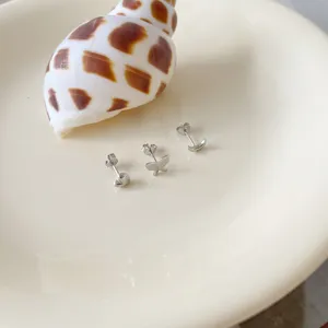Delicate silver stud earrings detail showing heart, butterfly, and moon shapes on plate.