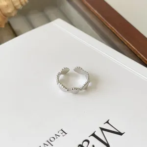 Detailansicht eines stilvollen silbernen offenen Rings mit filigranem Muscheldesign.