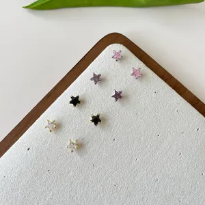 Close-up detail of multi-color zircon star stud earrings displayed on white tray.
