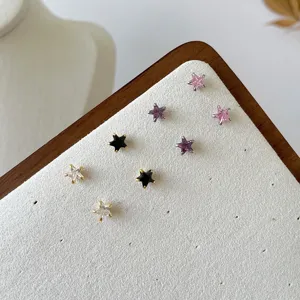 Close up of colorful cubic zirconia star stud earrings displayed on a white board.