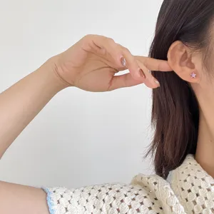 Close-up detail of purple star stud earrings showcasing delicate zircon craftsmanship on ear.