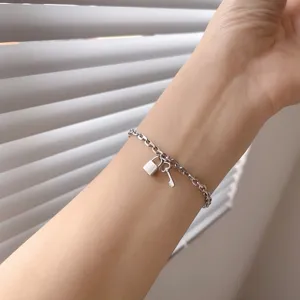 Detailopname van zilveren kettingarmband met miniatuur slot en sleutel hangers.
