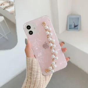Pink shell texture phone case detail with pearl chain strap and sparkling rhinestones.