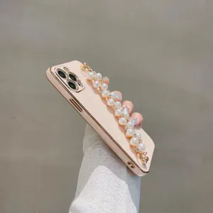 Pink electroplated phone case detail featuring elegant pearl bracelet chain and gold edge protection.