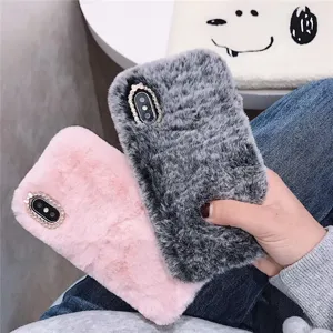 Plush phone case detail, soft furry texture with sparkling rhinestone camera frame, pink and grey.