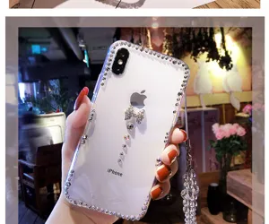 Detail shot of transparent rhinestone phone case with bowknot and lanyard for iPhone.