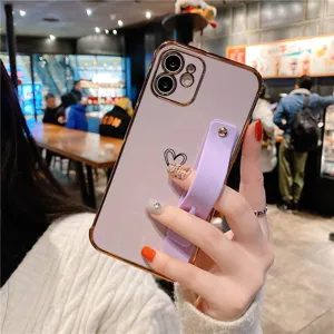 Electroplated purple phone case with heart pattern and wrist strap stand for Apple iPhone.