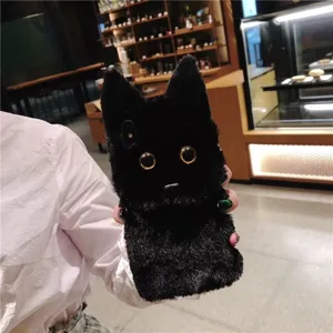 Close-up detail of cute black plush cat phone case with fluffy texture and shiny eyes.