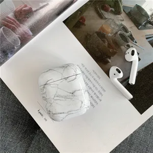 Detailed close-up of marble pattern AirPods protective case on magazine flatlay background.
