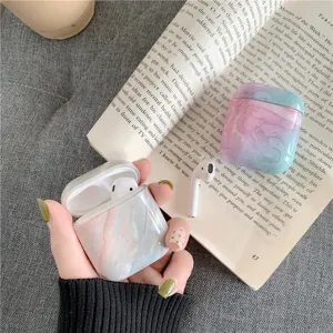 Detailed close-up shot of stylish marble pattern AirPods case with book background.