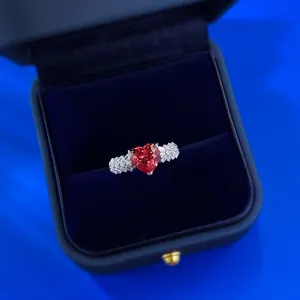 Nahaufnahme Detail eines atemberaubenden herzförmigen roten Edelsteinrings mit funkelnden Steinen.