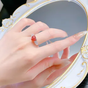 Detailaufnahme eines funkelnden Herz-Edelsteinrings in Sonnenuntergangsrot mit Zirkoniasteinen.