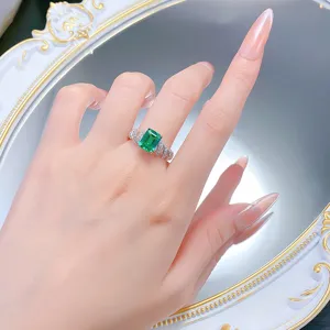 Detailansicht des Smaragdschliff Ringes mit grünem Edelstein und verdrehtem Band.