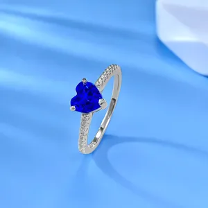 Primo piano dettagliato di un anello in argento sterling con gemma blu a cuore scintillante.