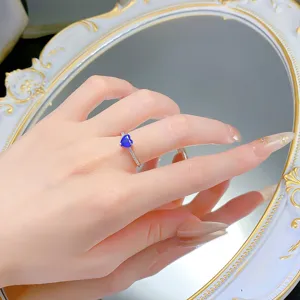Dettaglio ravvicinato di un anello in argento S925 con gemma blu a forma di cuore lucida.