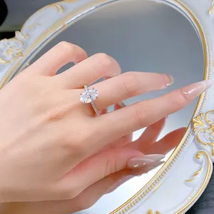 Close-up of elegant oval cut moissanite ring with pave band sparkling on hand model detail.