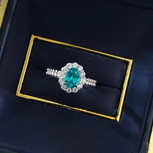 Nahaufnahme des silbernen ovalen Edelstein-Halo-Rings mit funkelnden Steinen in edler Box.