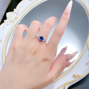 Close-up detail of a silver oval blue stone ring with wing side stones worn elegantly.