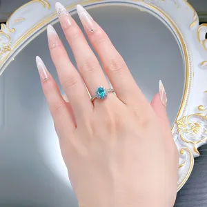 Eleganter Ring mit ovalem blau-grünem Edelstein, Halo und Perlenrand-Design aus Silber.
