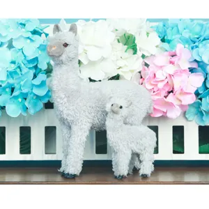 Primo piano dettagliato di una simpatica coppia di alpaca di peluche grigi con fiori.
