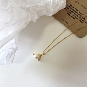 Elegante collana con ciondolo color oro con perla bianca e design geometrico ricurvo.