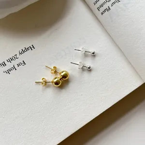 Minimalist gold and silver ball stud earrings close-up, chic daily minimalist jewelry.