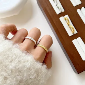 Detailaufnahme minimalistischer gerippter Silber- und Goldringe mit strukturierter Oberfläche.