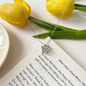 Detailed close-up of a sparkling silver hexagram pendant necklace on a book and tulip.