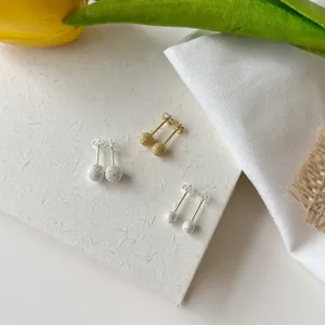 Detailed close-up view of simple sandblasted silver ball stud earrings, modern minimalist style.