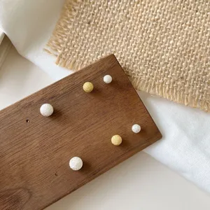 Close-up detail of S925 silver sandblasted small round ball earrings in gold and silver.