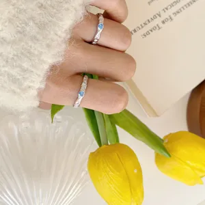 Close-up detail of sterling silver irregular heart ring with blue zircon worn on hand model.