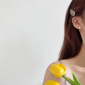 Elegant women minimalist round ball stud earrings paired with stylish chic hair clip accessory.