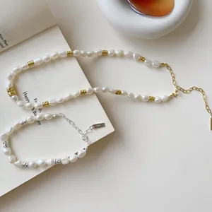Gros plan détail de collier et bracelet en perles baroques et dorées, style de bijoux.