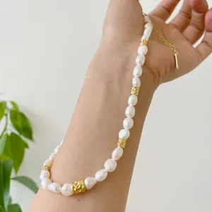 Gros plan détaillé d'un collier de perles d'eau douce baroques avec perles en or texturées.