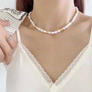 Gros plan détaillé sur le collier de perles d'eau douce baroque avec perles dorées porté.