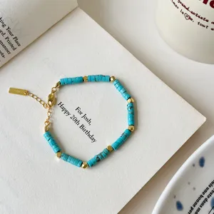 Close-up detail of turquoise beaded bracelet with gold metal spacers and extension chain.